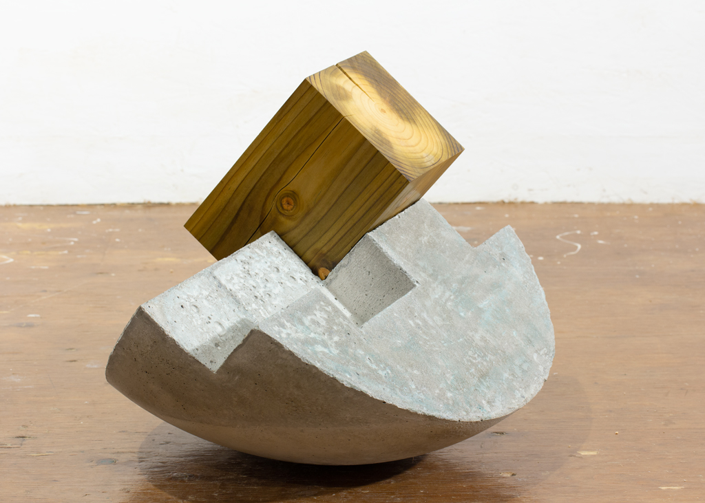 Sculpture de bois et de béton dont la base est ronde et instable.