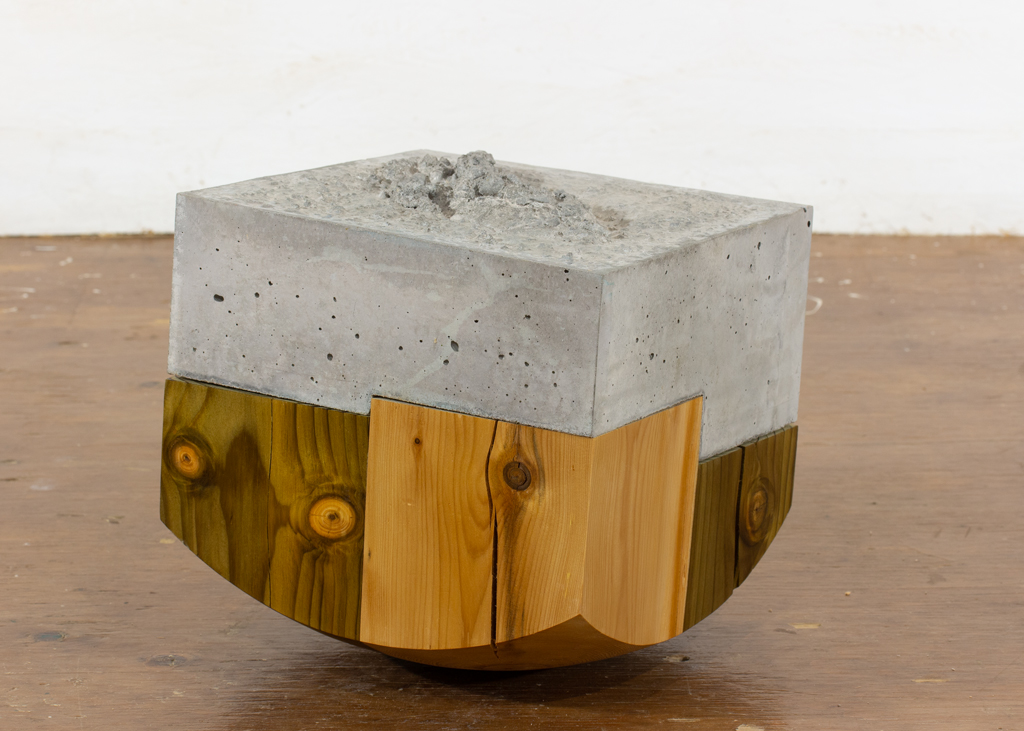 Sculpture de bois et de béton dont l'appui est de forme bombée.