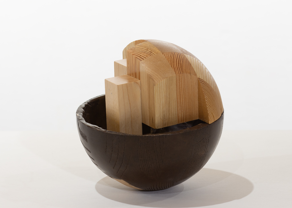 Sculpture sphérique composée partiellement de bois sculpté et de bronze.