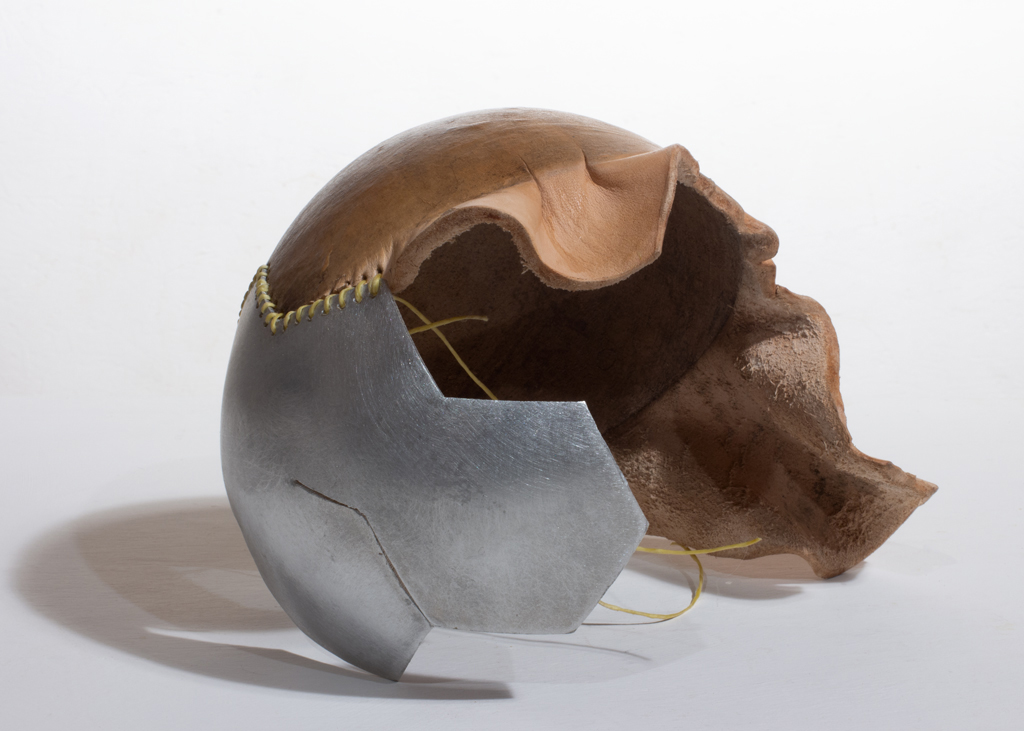 Petite sculpture ronde faite d'aluminium riveté et de cuir végétal formé. Les deux composantes sont cousues ensemble.