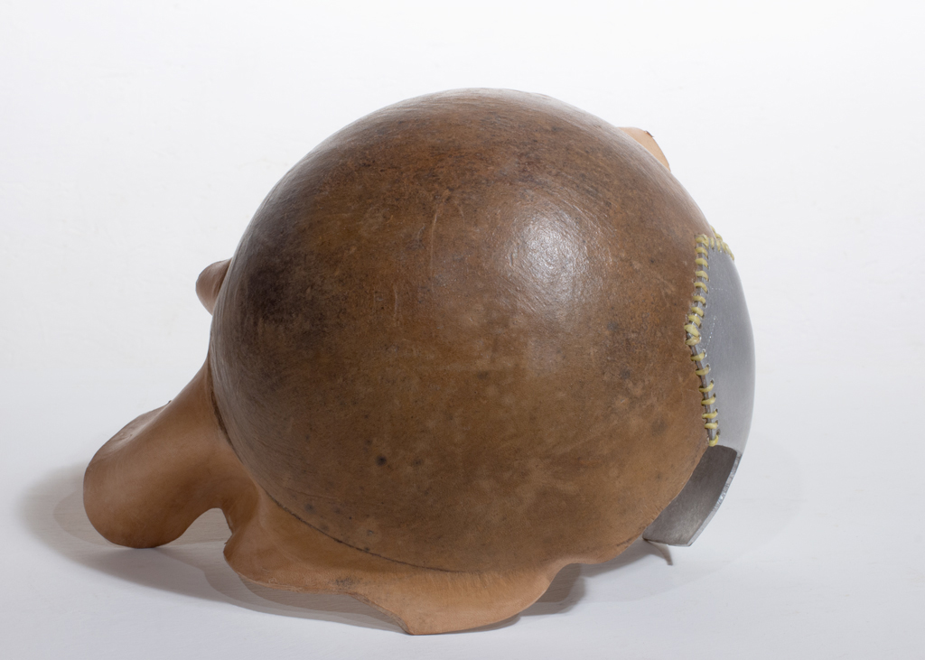 Petite sculpture ronde faite d'aluminium riveté et de cuir végétal formé. Les deux composantes sont cousues ensemble.