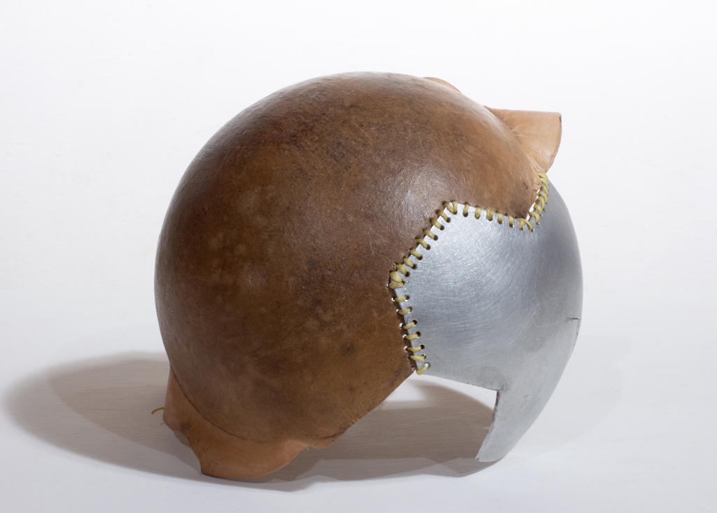 Petite sculpture ronde faite d'aluminium riveté et de cuir végétal formé. Les deux composantes sont cousues ensemble.