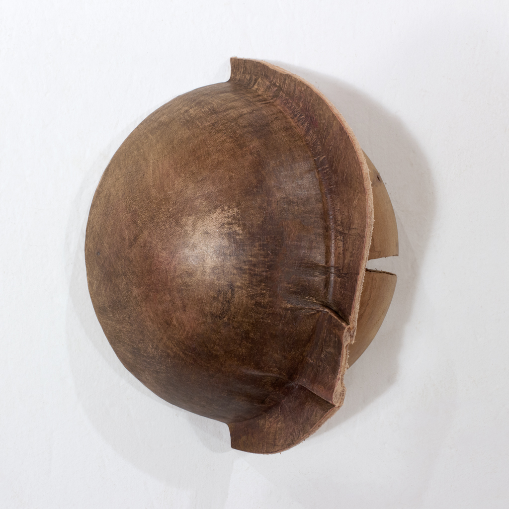 Petite sculpture en forme de dôme. Une partie est faite de cuir végétal formé, l'autre en bois sculpté. Sur cette image, on voit la pièce posée à la verticale contre un mur.