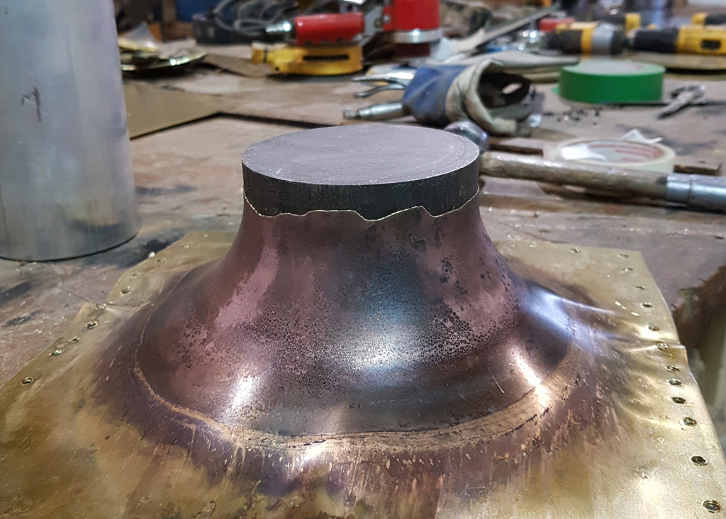 Sculpture de laiton chaudronné en cours de réalisation. On y voit l'une des composantes étirée par le passage d'un cylindre d'acier.