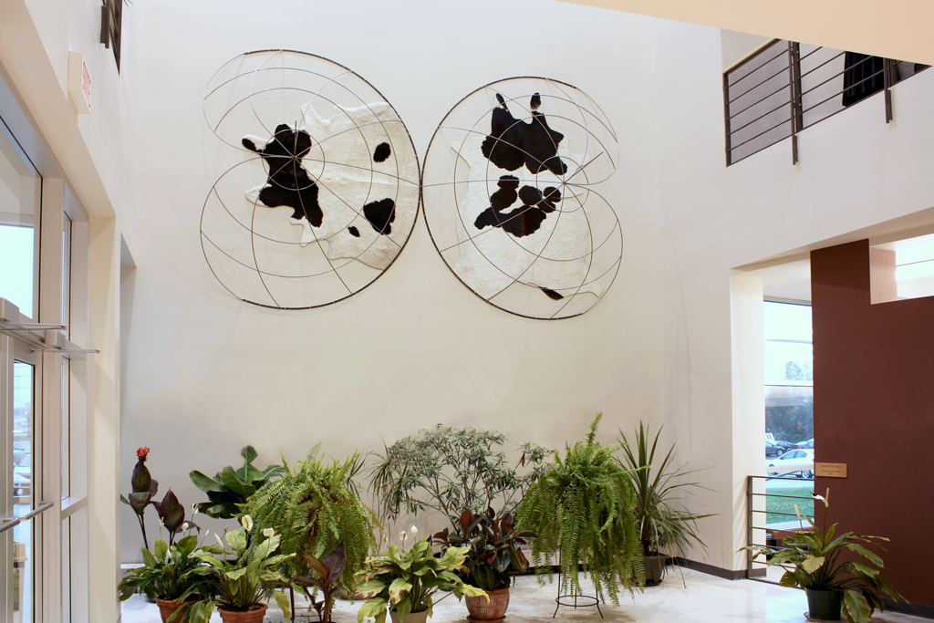 Œuvre d'art murale représentant une mappemonde. Les continents sont tracés en noir et blanc à l'aide de peaux de vaches de chawue côté.