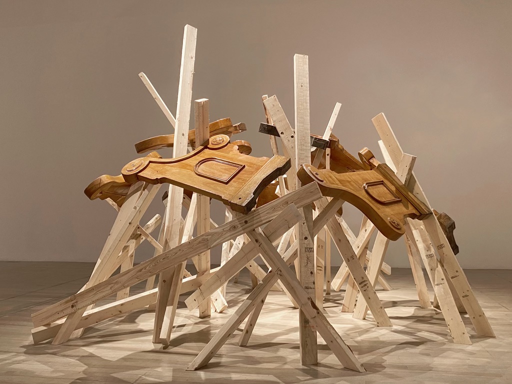 Sculpture prenant la forme d'un dôme, faite d'un assemblage de bancs d'église et de 2x4 d'épinette.