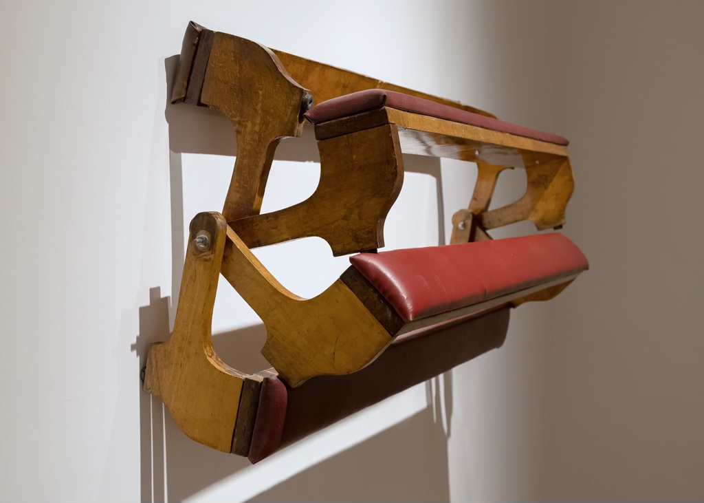 Sculpture murale faite d'un assemblage d'agenouilloirs d'église.