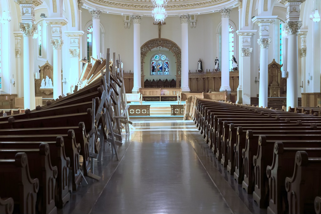Détail d'une installation sculpturale dans une église. Les bancs sont soulevés à l'aide de bois d'œuvre pour former une grande vague.