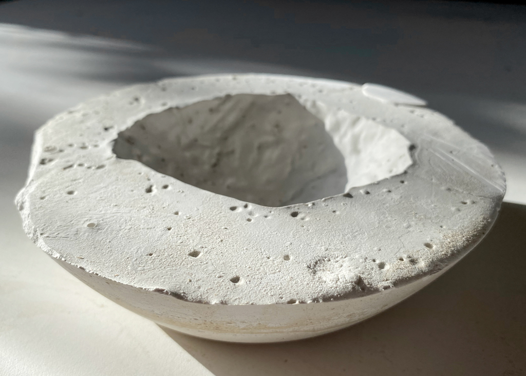 Petite coulée de plâtre creuse, la cavité évoquant l'empreinte d'un objet serti à l'intérieur d'un autre.