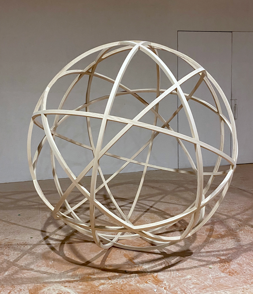 Grande sphère formée de multiples arcs de bois amalgamés les uns avec les autres.